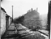[terraced houses being demolished and cobbled road]